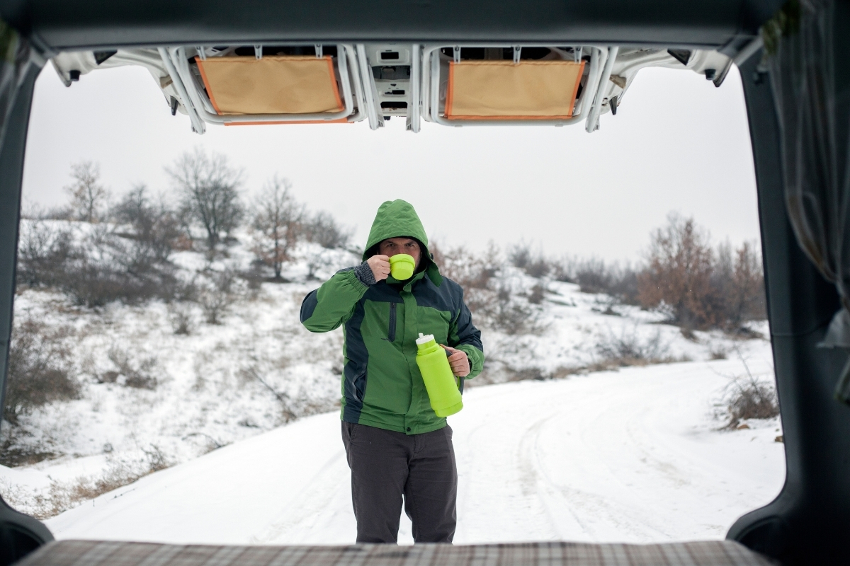 Vue d'un homme dans la neige depuis l'arrière d'un van ouvert